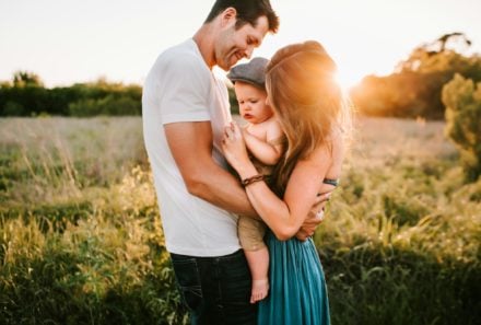 Family holding baby in grass