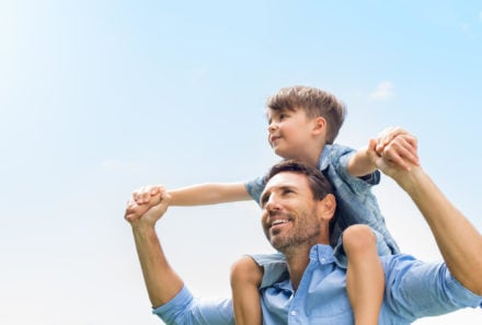 Father giving adoptive son a ride on his shoulders